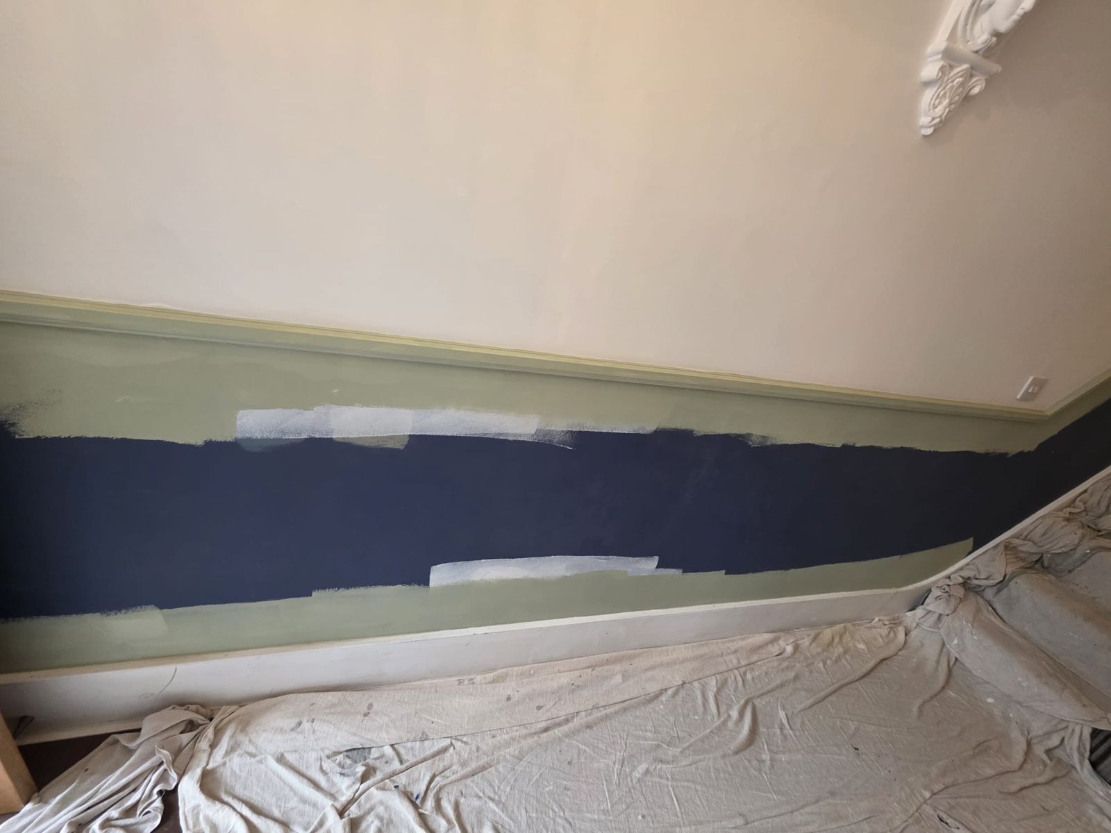 Navy wall being painted over with sage green