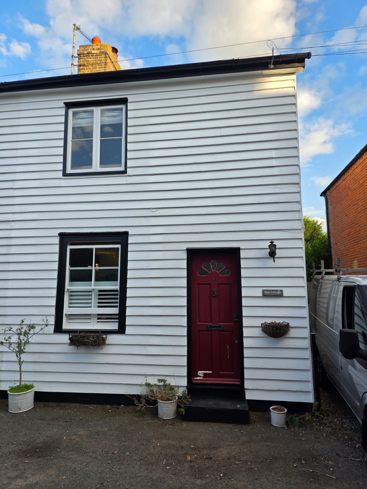Weatherboard cottage front in white with a red front door