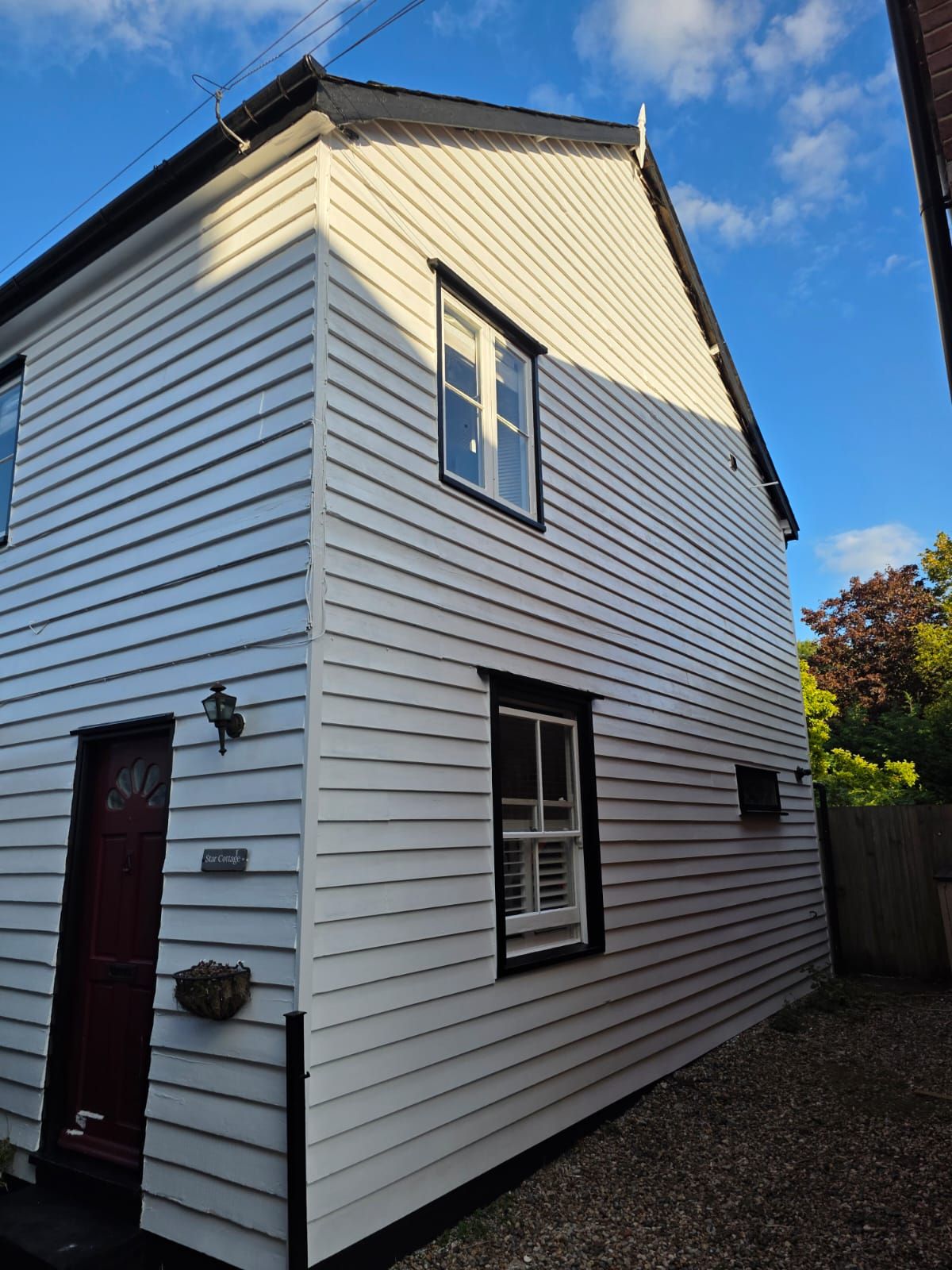 Side of the cottage in white weatherboard