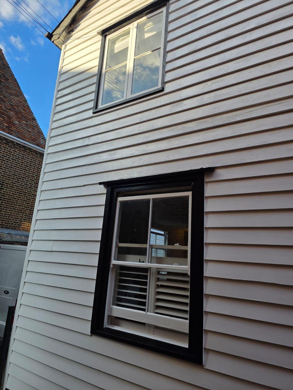 Window in black frame against white weatherboard