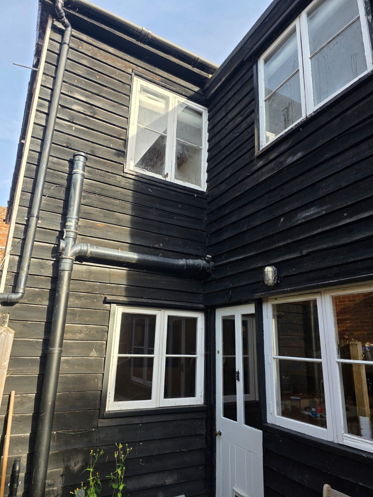 Rear windows in white against black weatherboard